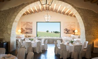 a large , white dining room with multiple tables and chairs set up for a formal event , possibly a wedding reception at Castello Camemi