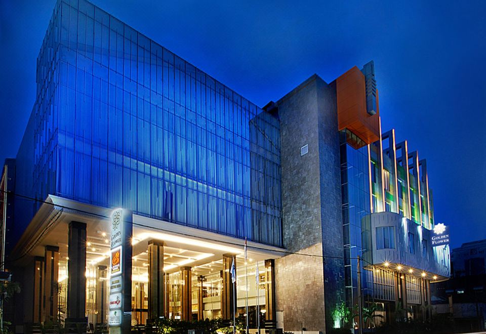 a modern building with blue lights and a large glass facade , illuminated by street lights at night at Golden Flower by Kagum Hotels