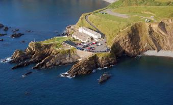 a bird 's eye view of a coastal area with a road winding through the landscape at Hartland Quay Hotel