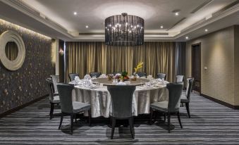 a large dining room with a round table surrounded by chairs , and a chandelier hanging above at Carlton Hotel