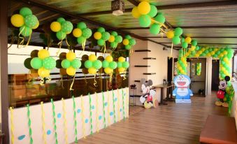 a party room with green and yellow balloons hanging from the ceiling , creating a festive atmosphere at Lime Tree Hotel
