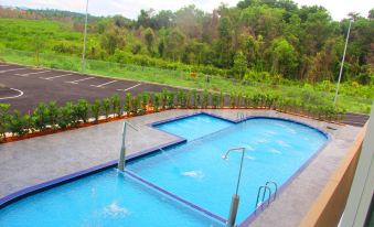an outdoor swimming pool surrounded by grass and trees , with a basketball court in the background at 906 Premier Hotel