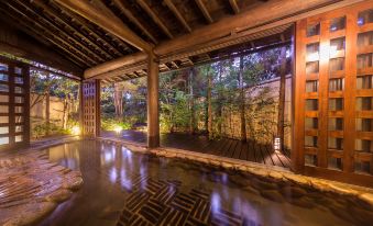 a wooden building with a terrace and a small garden , illuminated by lights at night at Miyako