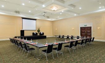a large conference room with multiple tables and chairs , a projector screen , and a podium at Rydges Southbank Townsville, an EVT hotel