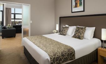 a large bed with a gold and white patterned comforter is in the center of a room at Rydges Mackay Suites, an EVT hotel