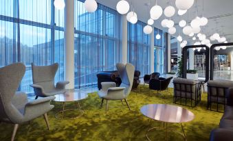a modern lounge area with large windows , white chairs , and black tables , under hanging lights at Gothia Towers & Upper House
