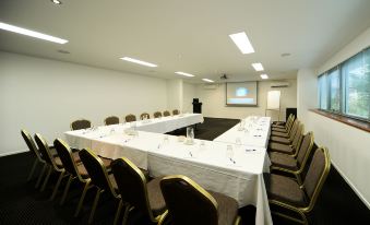 a conference room with a long table covered in white tablecloths , surrounded by chairs and set up for a meeting at Airlie Beach Hotel