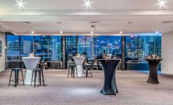 a room with tables and chairs set up for a party , overlooking a cityscape at night at Mercure Brisbane Spring Hill