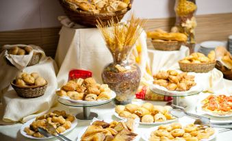 a table is filled with various types of pastries and breads , including croissants and bread rolls at Aqua Hotel