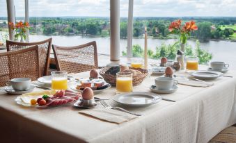 a dining table set with a variety of breakfast items , including eggs , oranges , and bacon at Hotel Bellevue