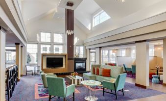 a spacious living room with high ceilings , large windows , and multiple seating arrangements , including couches , chairs , and a coffee table at Residence Inn Auburn