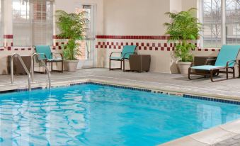 an indoor swimming pool surrounded by lounge chairs , with people enjoying their time in the pool area at Residence Inn Cranbury South Brunswick