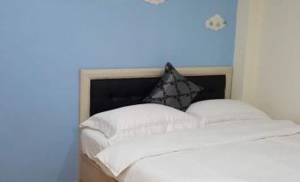 a bed with white sheets and a black pillow is in a room with blue walls at Leisure