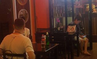 two people are sitting at tables in a restaurant , with one of them wearing a face mask at Cheaper Room