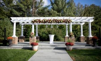 a white gazebo with flowers and greenery , surrounded by brick pillars and set in a garden setting at Crowne Plaza Suffern-Mahwah, an IHG Hotel