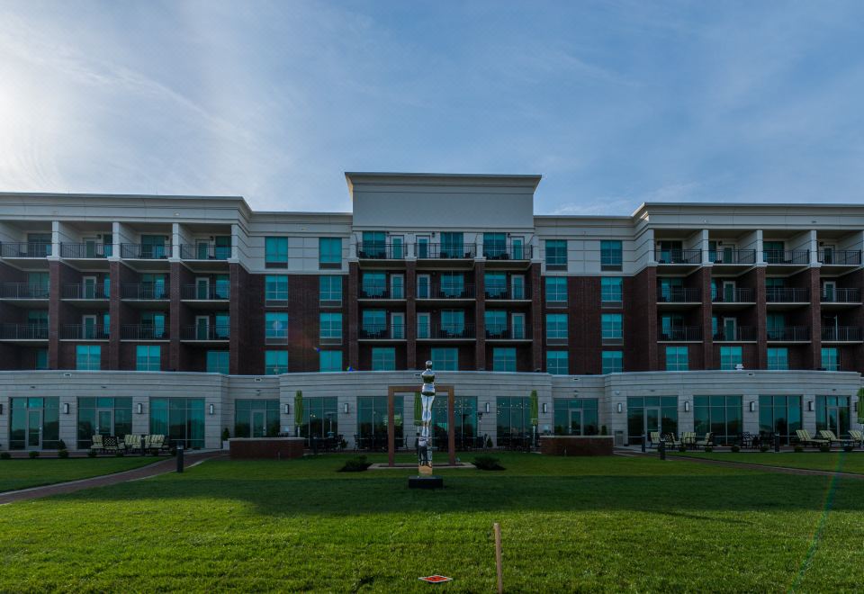 a large brick building surrounded by grass and trees , with a grassy field in front of it at Holiday Inn Owensboro Riverfront