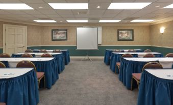 a conference room with rows of tables and chairs , a whiteboard , and two framed pictures on the wall at Sonesta ES Suites San Francisco Airport San Bruno