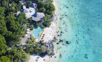 aerial view of a resort on a tropical beach , with a large swimming pool surrounded by palm trees at Small Luxury Hotels of the World - Pacific Resort Aitutaki
