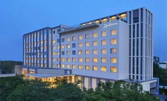 "a large hotel with a sign that says "" pullman "" is lit up at night" at Radisson Hotel Agra
