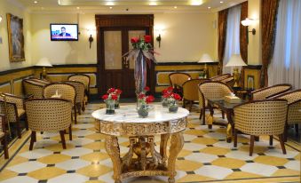 a luxurious hotel lobby with gold - plated chairs , a marble table , and floral arrangements , as well as a television screen on the wall at Golden Hotel