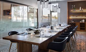 a long dining table is set with wine glasses , plates , and silverware in a modern restaurant at Marriott Dallas Las Colinas