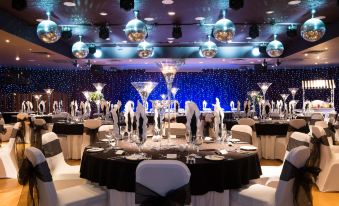 a well - decorated banquet hall with tables covered in black tablecloths and silver wine glasses filled with champagne at Holiday Inn Aberdeen - West
