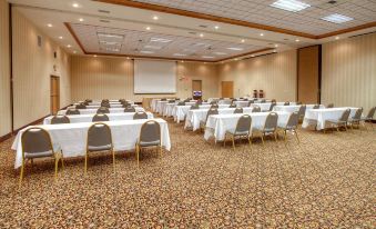 a large conference room with multiple rows of chairs arranged in a semicircle , and a projector screen mounted on the wall at Hampton Inn Billings