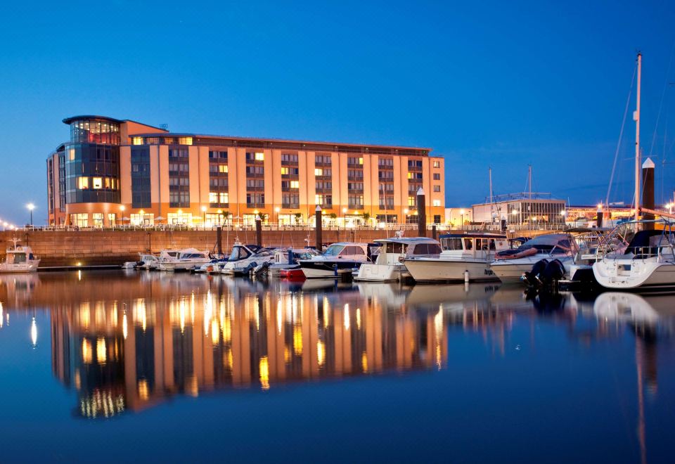 a marina at night , with several boats docked and a building in the background reflecting on the water at Radisson Blu Waterfront Hotel, Jersey