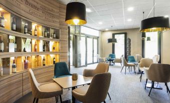 a modern lounge area with wooden walls , pendant lights , and various seating arrangements , including couches and chairs at Mercure Libourne Saint Emilion