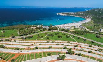 an aerial view of a beautiful beach and ocean with white sand and blue water , surrounded by greenery at MClub Marmorata