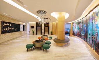 a modern hotel lobby with a large chandelier , multiple seating areas , and a large tree at Hotel Ciputra Cibubur Managed by Swiss-Belhotel International