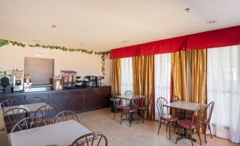 a dining area with several tables and chairs , along with a coffee station in the background at Executive Inn