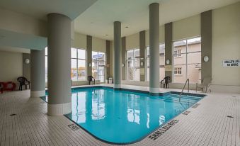 an indoor swimming pool with a large window , surrounded by white columns and a tiled floor at Comfort Hotel