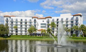 a white building with a fountain in front of it and palm trees in the background at Inn at Pelican Bay