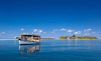 a boat with a large window is floating on a body of water near an island at Vilamendhoo Island Resort & Spa