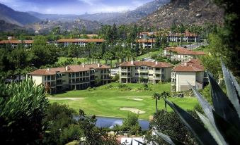 a large golf course surrounded by buildings and trees , with a mountainous background in the background at Hyatt Vacation Club at the Welk, San Diego