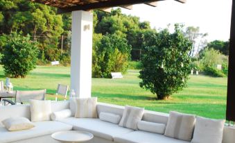 a white couch is placed under a pergola , overlooking a lush green field with trees in the background at Skiathos Holidays Suites & Villas