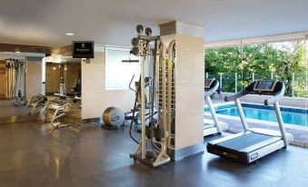 a gym with various exercise equipment , including treadmills and weight machines , near a swimming pool at DiplomaticHotel