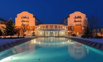 a large swimming pool is surrounded by a hotel building with balconies and lights on at The Monarch Hotel