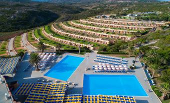 aerial view of a resort with multiple swimming pools , sun loungers , and palm trees surrounded by hills at MClub Marmorata