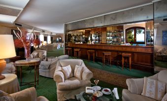 a well - decorated hotel lobby with various seating options , including couches , chairs , and a bar at Grand Hotel Baia Verde