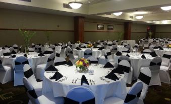 a large banquet hall filled with round tables and chairs , ready for a formal event at Casino Queen Hotel
