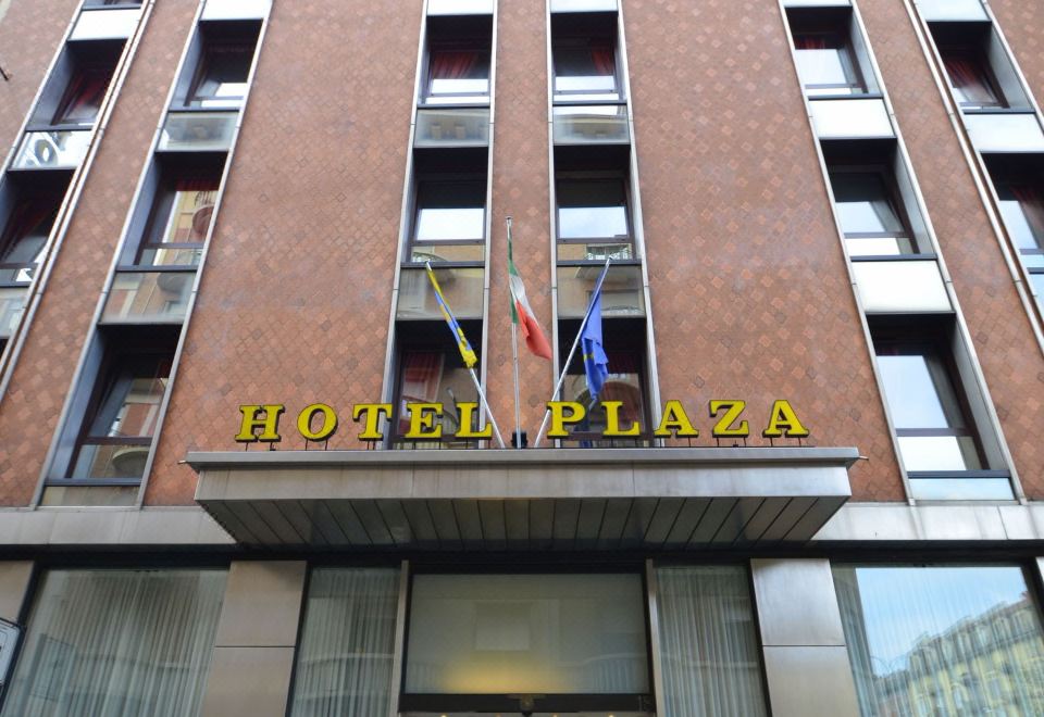 a large hotel building with multiple flags hanging from the front , creating a festive atmosphere at Hotel Plaza