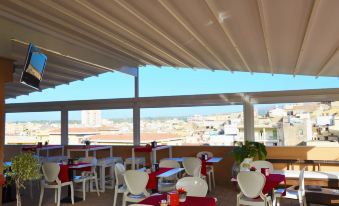 a restaurant with red tablecloths and white chairs is situated on a rooftop patio , overlooking the city at Hotel Flora