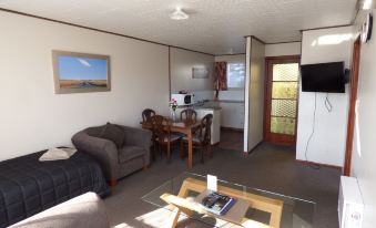 a living room with a couch , coffee table , and dining table in front of a kitchen area at Anchor Motel