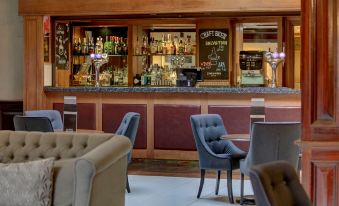 a bar with a variety of chairs and tables , along with bottles on the counter at Quorn Country Hotel