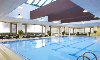 an indoor swimming pool with a large glass roof , allowing natural light to fill the space at Sheraton Grande Tokyo Bay Hotel