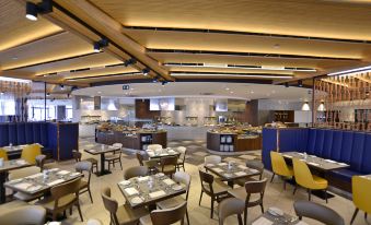 a large , modern restaurant with multiple dining tables and chairs arranged in an open space at DoubleTree by Hilton Malta