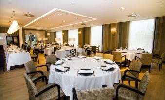 a large dining room with round tables covered in white tablecloths and chairs arranged around them at Hotel Bahia