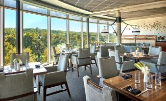 a restaurant with large windows overlooking a forested area , providing a stunning view of the outdoors at The Fontaine